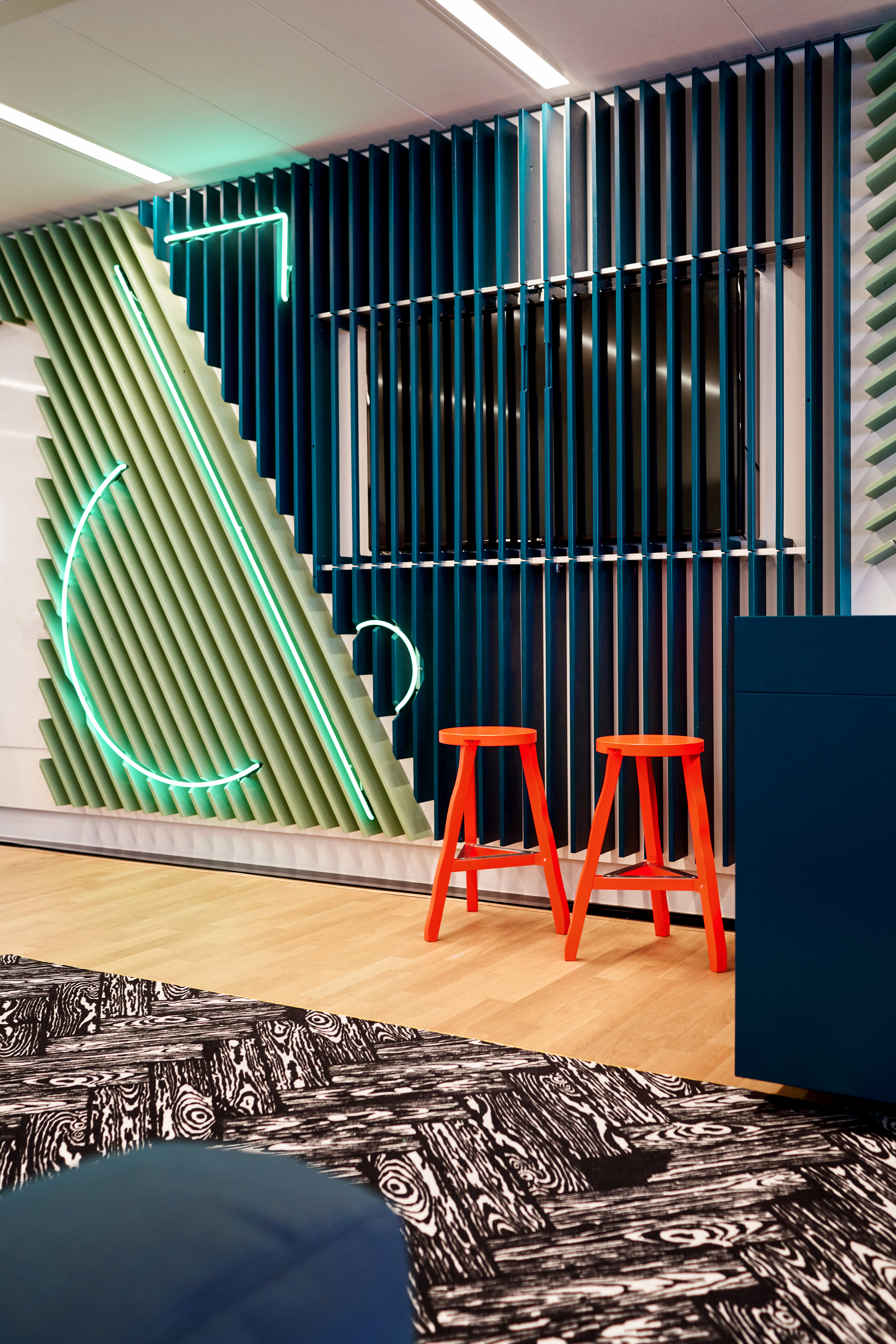 De langste wand van het kantoor heeft meerdere functies gekregen. Scrummen, presenteren. In de lattenwand is de identiteit van het bedrijf groots zichtbaar gemaakt door middel van een neon uitvoering van het bedrijfslogo. Een scherm is verwerkt in de wand en is alleen zichtbaar wanneer de latten naar de zijkant worden geschoven. fotografie Philip Jintes @ Phenster
