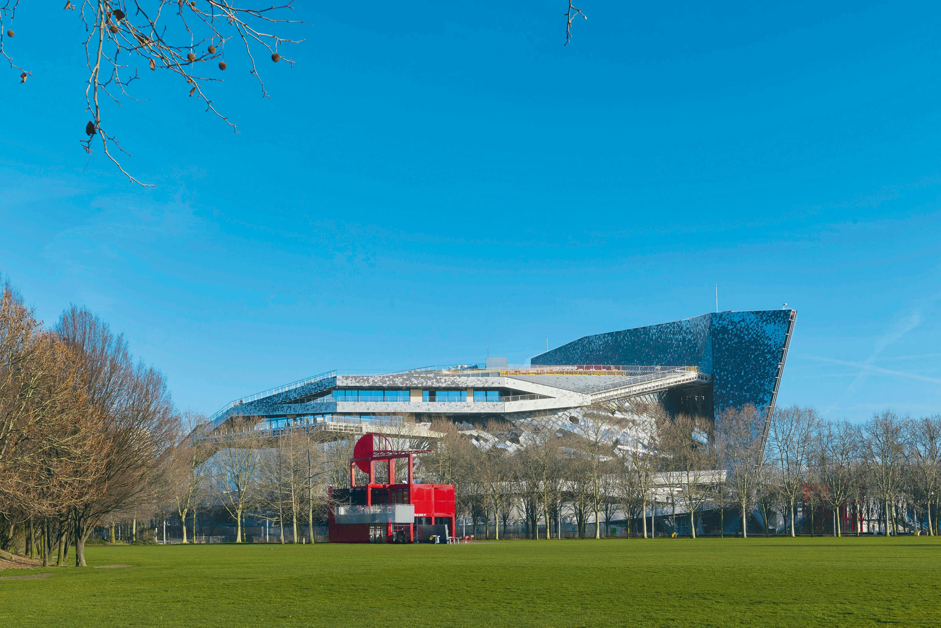 De Philharmonie gezien vanuit het Parc de la Villette, met op de voorgrond een van de karakteristieke, rode follies die zijn ontworpen door Bernard Tschumi. Foto Montagu-Pollack