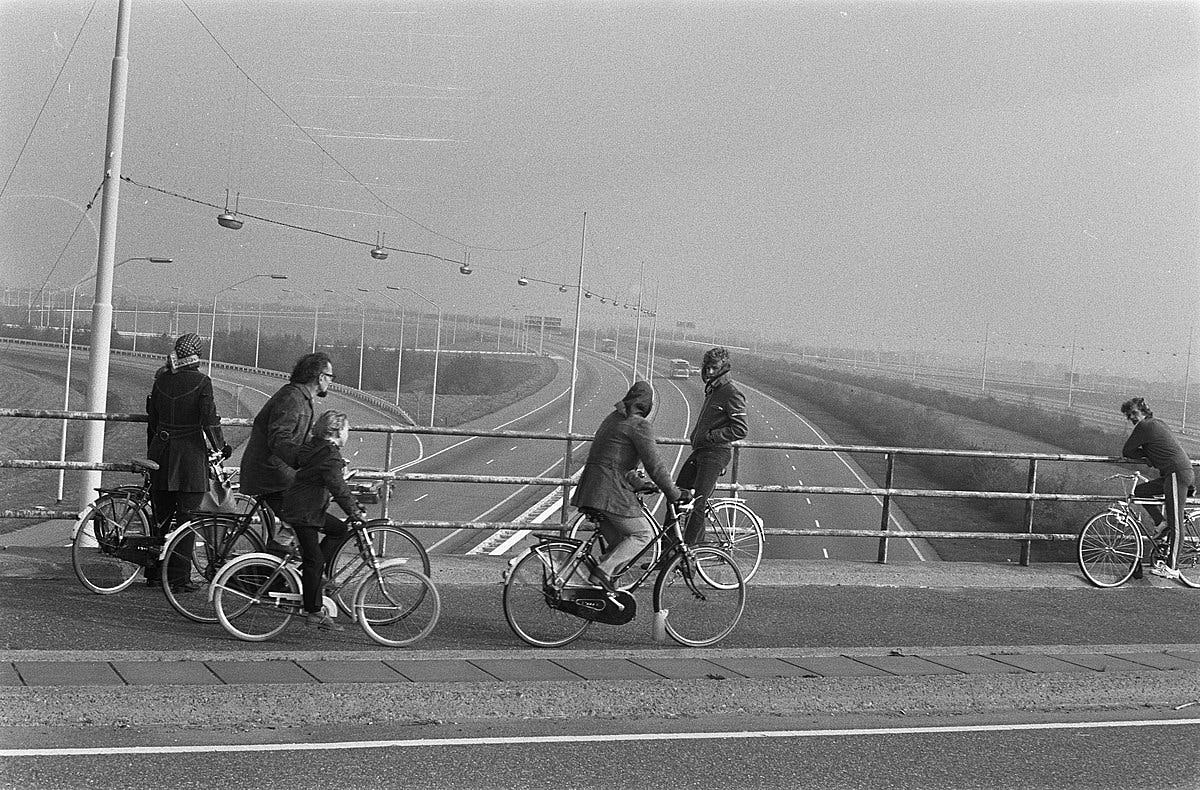Fietsers op een viaduct bekijken een lege autosnelweg tijdens de autoloze zondagen in 1973. Beeld Wikimedia Commons