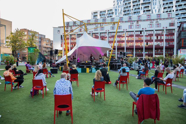 Mensen gaan naar een openluchtconcert op het Schouwburgplein in Rotterdam. Beeld Fleur Beerthuis. 
