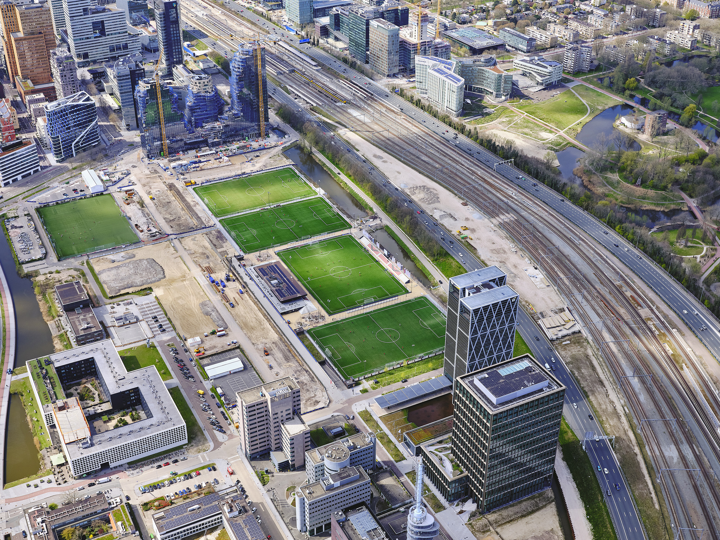 Nederland, Noord-Holland, Amsterdam, april 2021: Zicht op de Zuidas, deelgebied Ravel met velden van AFC (Amsterdamsche Football Club). Boven in beeld de Beethovenstraat met in aanbouw gebouw Valley (Winny Maas MVRDV). Beeld Siebe Swart