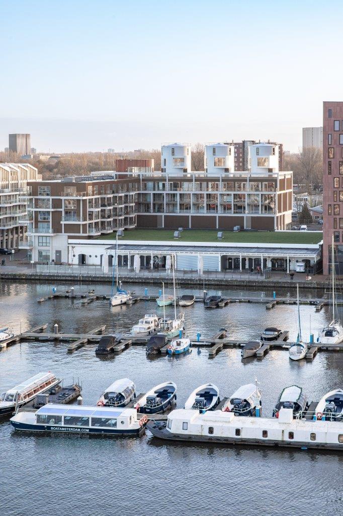 The Harbour Club kreeg een L-vormige nieuwbouw van zes lagen die de oude wijnterminal omarmt. Zo sluit het complex aan op de typologie van de nieuwbouw ernaast. Beeld Thijs van Stigt