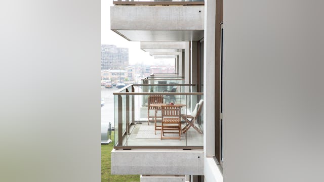 Over de oude wijnterminal kragen eenzijdig georiënteerde woningen vijf meter uit. Hun half-inpandige balkons kijken uit over de haven en het nieuwe groene dak van de terminal. Beeld Thijs van Stigt