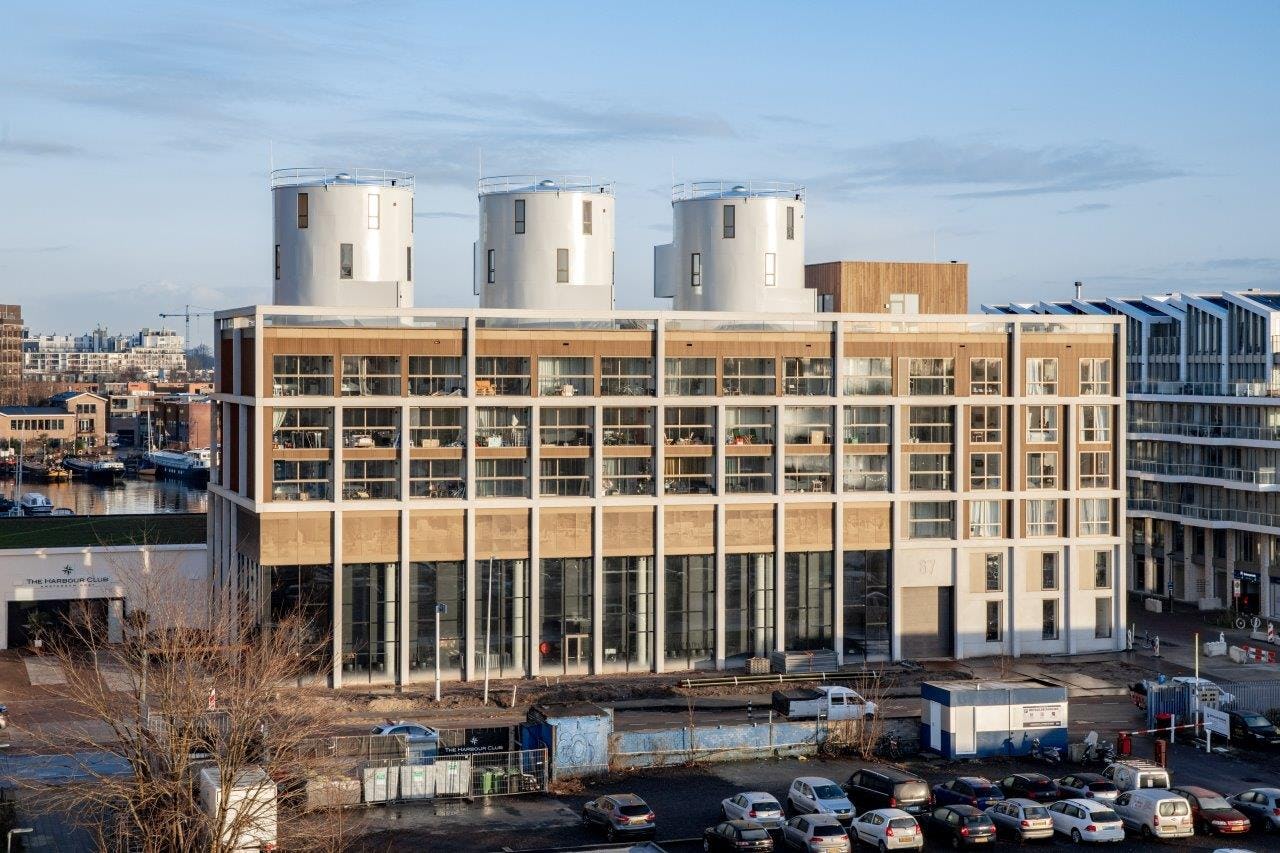 Betonnen kaders zijn ingevuld met glas en bronskleurig aluminium waarmee de gevel aan de oude industriële haven met zijn pakhuizen refereert. Beeld Thijs van Stigt