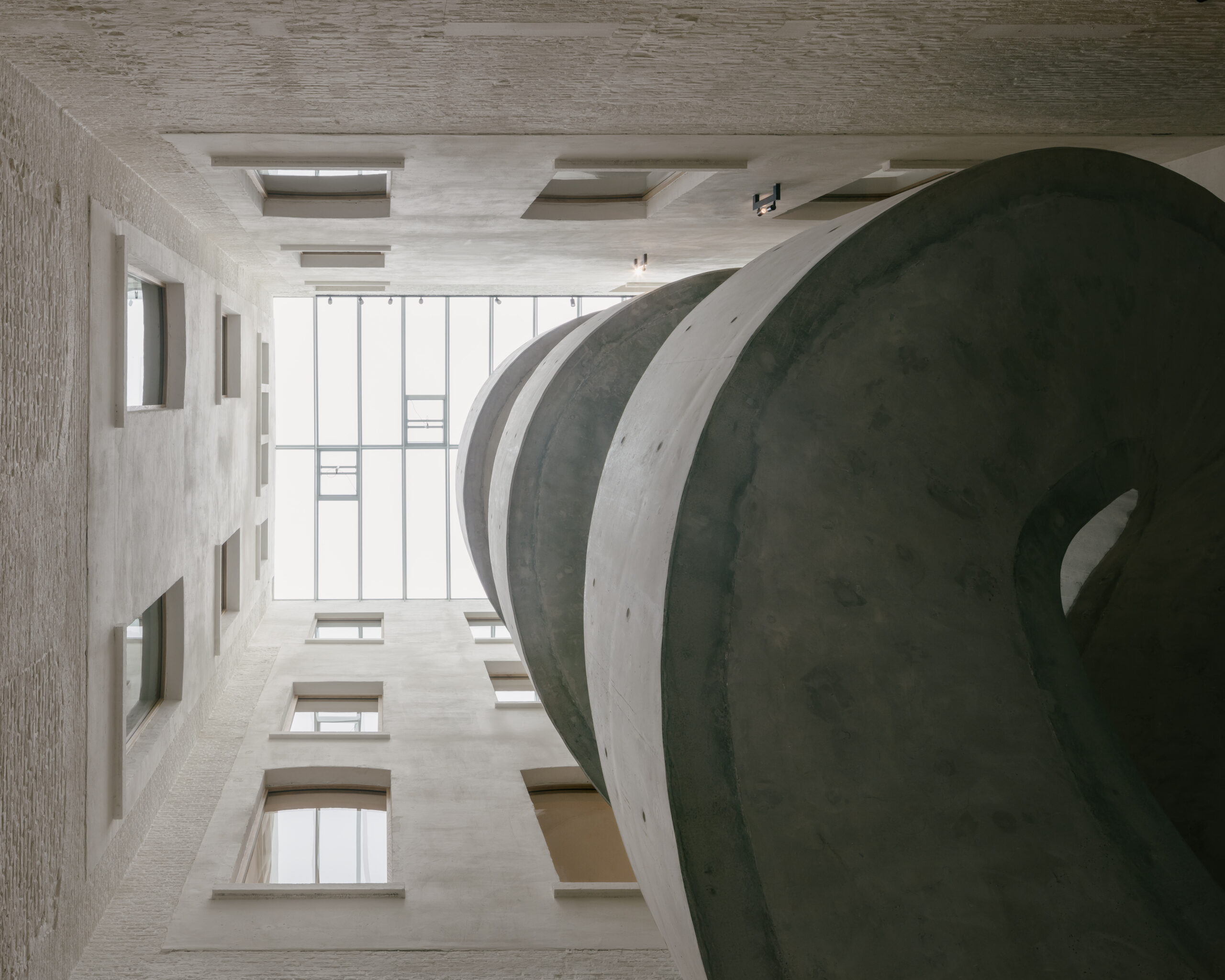Eén van de meest opvallende nieuwe elementen is de monumentale, vrijdragende wenteltrap in ter plaatse gestort zichtbeton.  Beeld Stijn Bollaert